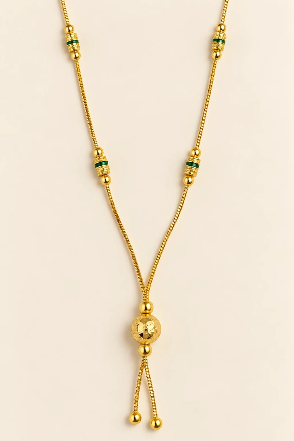 Aarohi gold-tone mangalsutra with green-banded engraved gold beads and a hammered gold ball lariat drop