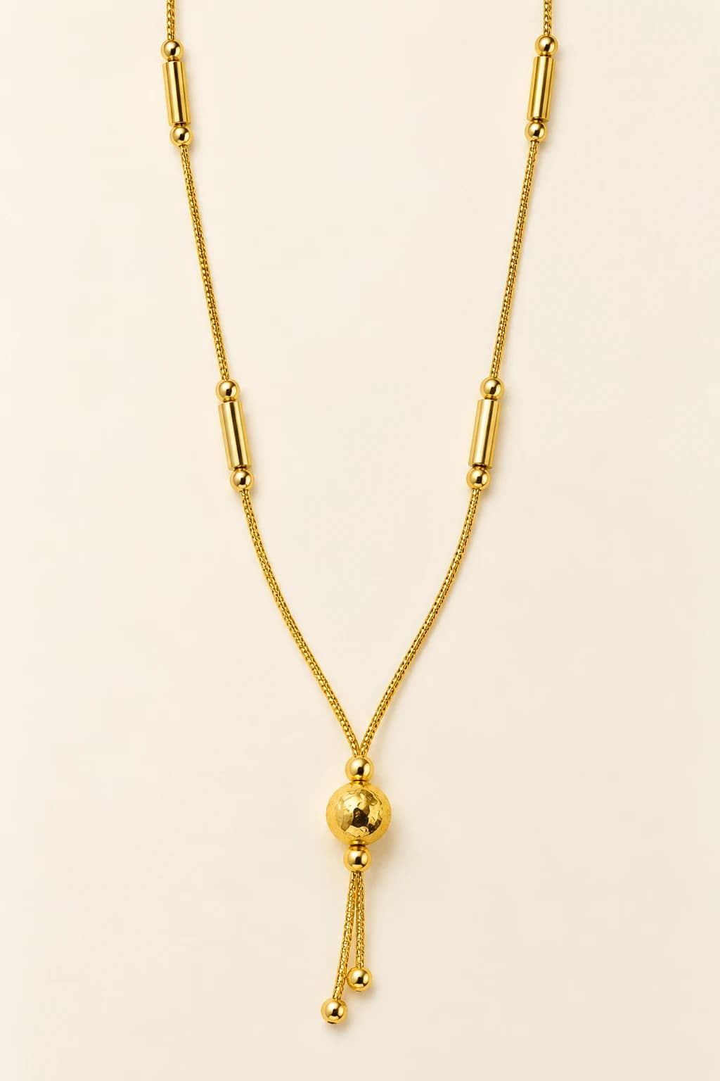 Kiara gold-tone mangalsutra with polished tube beads and a hammered gold ball lariat drop