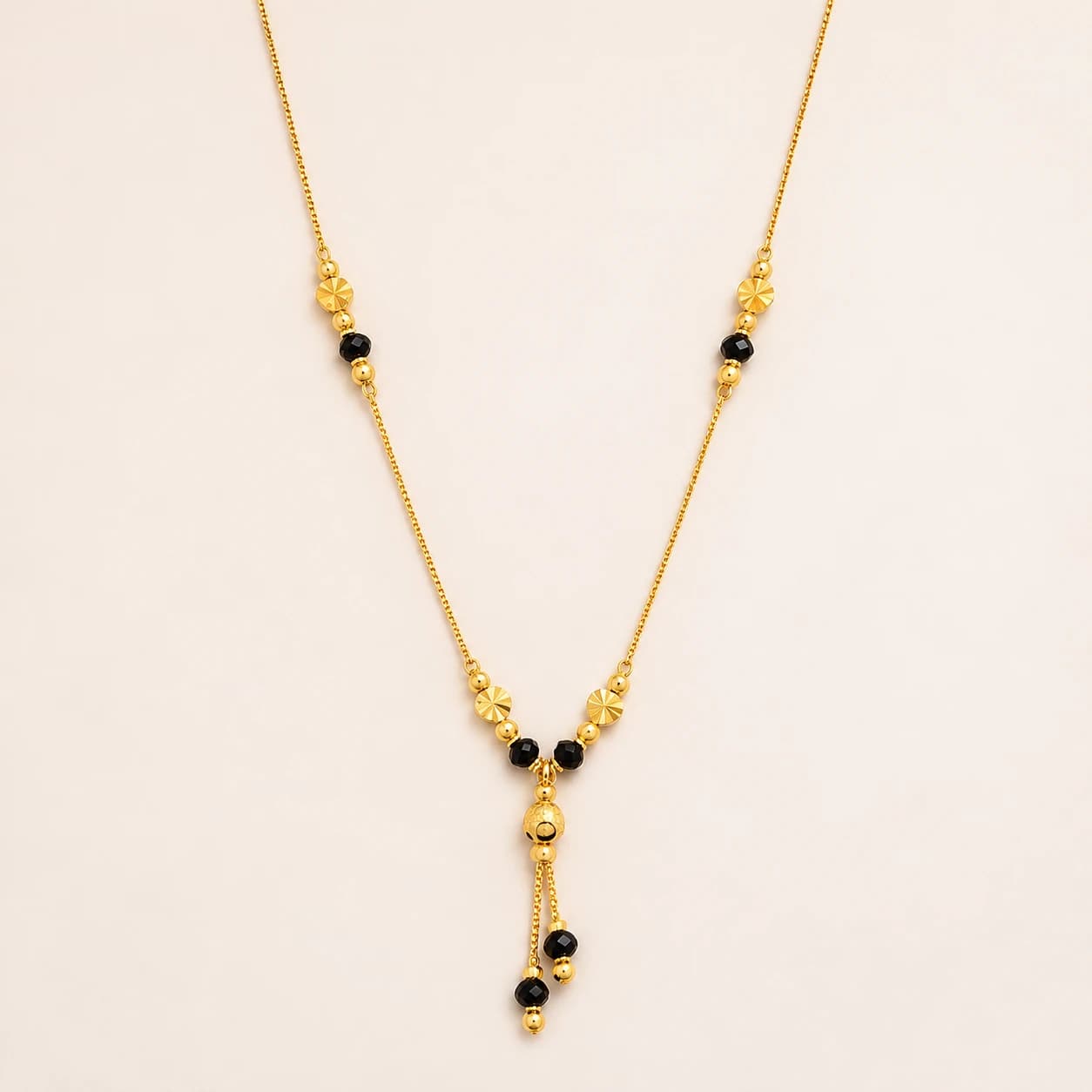 Riya gold-tone mangalsutra with faceted black beads, sunburst-cut gold discs and a double tassel drop