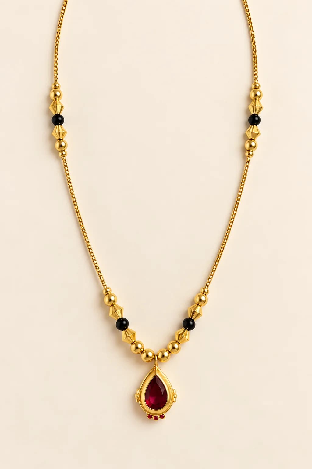 Siya gold-tone mangalsutra with pear-shaped red stone pendant, black beads and faceted gold beads